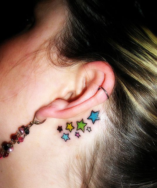 Colorful star tattoos behind the ears
