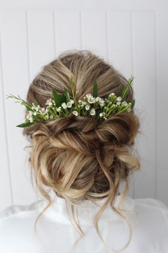 Wedding Hairstyle Updo with greenery and florals as accessories .