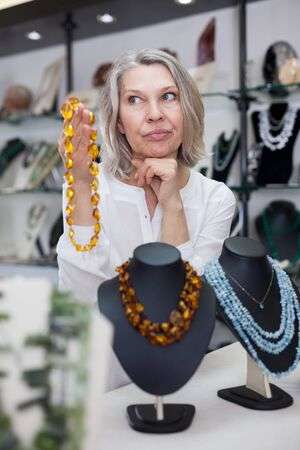 Adult Woman Chooses Jewelry From Turquoise And Amber Jewelery .