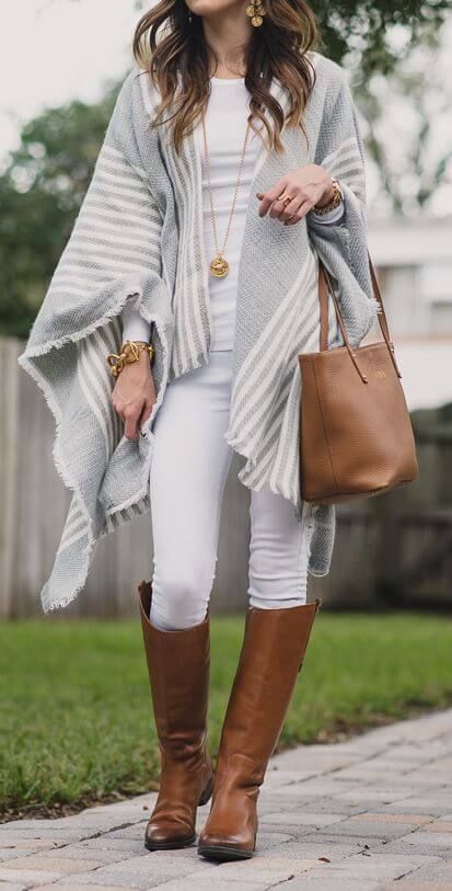 Woman wearing white jeans, white top, gray and white poncho, brown .